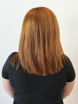 Foto "antes": vista trasera de una mujer con cabello castaño claro desigual de longitud media y raíces crecidas antes de la coloración.