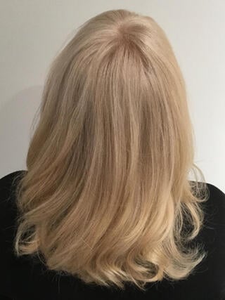 After Photo: rear view of woman with medium length even blonde hair after color.
