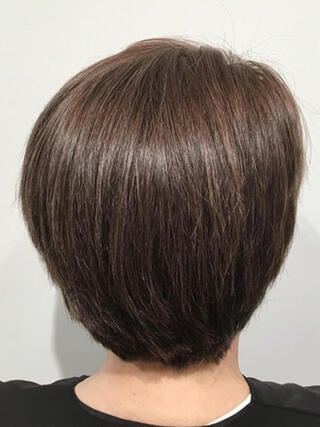 Foto "después": vista trasera de una mujer con cabello castaño corto sin canas después de la coloración.