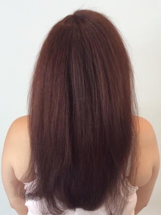 After photo: rear view of woman with long healthy red hair after color.