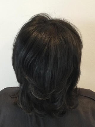 Foto "después": vista trasera de una mujer con cabello corto y negro sin canas después de la coloración.
