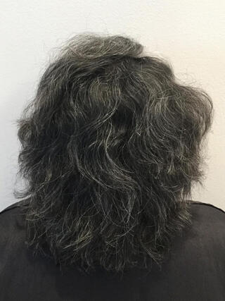 Foto "antes": vista trasera de una mujer con cabello negro corto con muchas canas antes de la coloración.